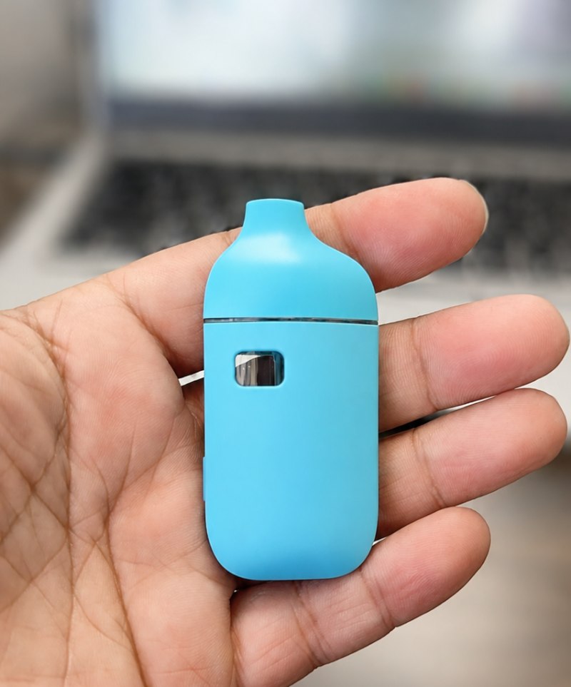 Compact D121 1 gram disposable vape hardware held in hand showing blue body and oil window