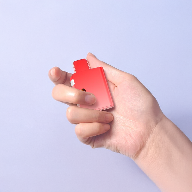 Hand holding a red electronic device against a light purple background